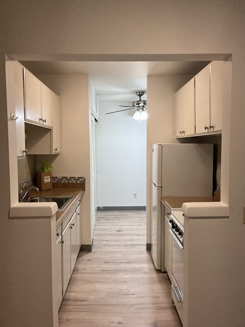 A kitchen with white cabinets and a white refrigerator.
